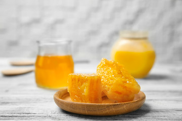 Wooden plate with fresh honeycombs on table