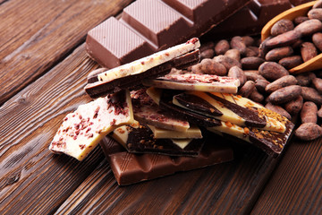 Dark chocolate pieces, stacks and cocoa beans, culinary background.