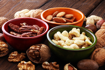 bowls with mixed nuts on wooden background. Healthy food and snack. Walnut, pecan, almonds, hazelnuts and cashews.
