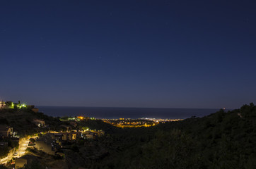 Night panorama above quiet touristic town on mediteranean shore near sea with stars on sky