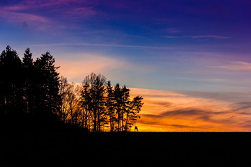 Obraz premium Evening orange sunset over field and forest, Czech republic