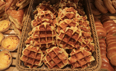 Many Fresh Baked Belgian Waffles in a Basket with another Delicious Pastries 