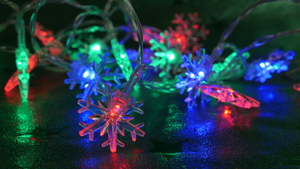 Colorful lights on an electronic Christmas tree chain in many colors on a green background. The climate of the upcoming Christmas.