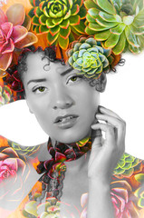 Portrait of a sexy beautiful african american girl with an afro hairstyle, with doble exposure of exotic plants in her head and body, in a white background, black and white effect