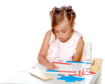 A little girl is studying Montessori stuff.