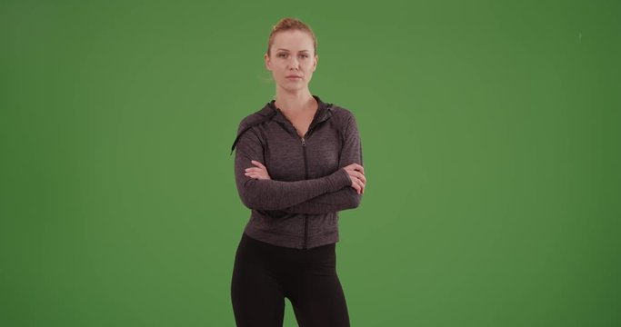 Strong woman athlete standing on green screen. On green screen to be keyed or composited. 