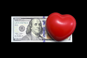 Fototapeta na wymiar red heart on one hundred dollar bill