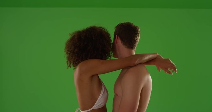 Closeup of romantic mixed race couple holding each other while the sun sets on green screen. On green screen to be keyed or composited. 