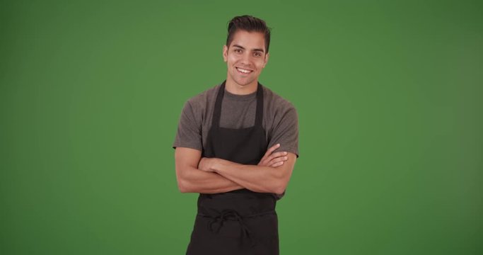 Happy handsome young Latino waiter on green screen. On green screen to be keyed or composited. 