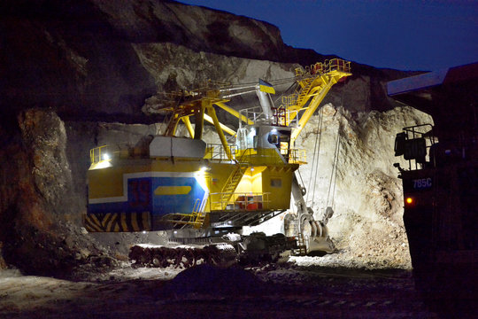 Excavator works in a quarry at night