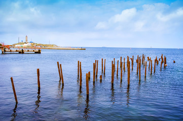 piles stick out of the water of the sea