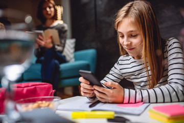 Girl doing homework and using smart phone