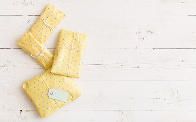 Top view on four nice Christmas, birthday or any other celebration presents warpped in yellow dotted paper with cord and tag on white background