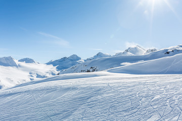 Off-piste ski slope with trace from skis and snowboards at sun winter day. Kavkaz mountains. - obrazy, fototapety, plakaty