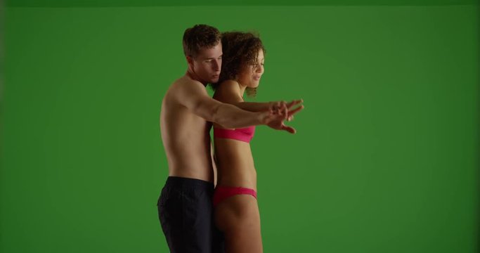 Profile view of couple standing on beach and holding hands on green screen. On green screen to be keyed or composited. 