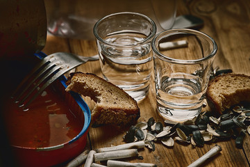 Open empty canned fish,fork,shots, seeds husk, bitten bread and cigarette butt 