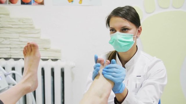 doctor of podiatr makes foot massage to a young girl in clinic