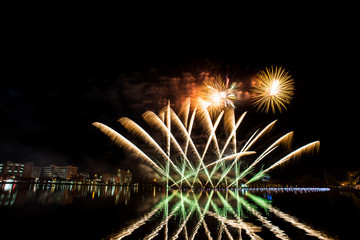 Beautiful fireworks in the night sky on the water surface.