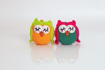 Two colorful handmade knitted owls placed on a white background
