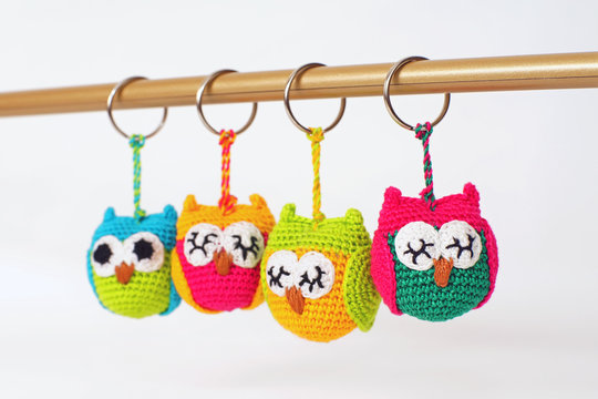 Cute colorful handmade knitted owls hanging on a white background