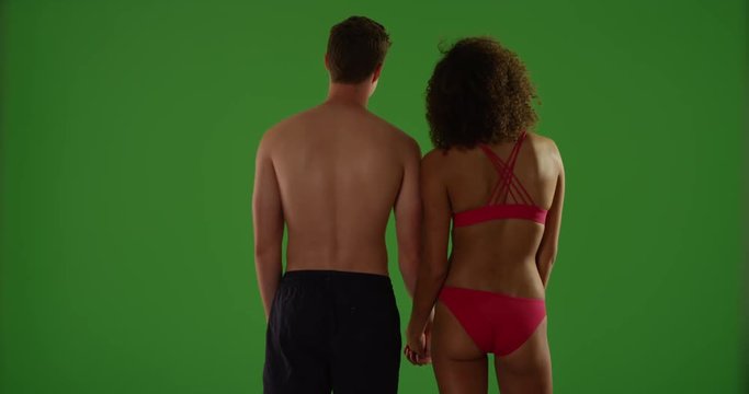 Portrait of interracial couple watching sunset on green screen. On green screen to be keyed or composited. 
