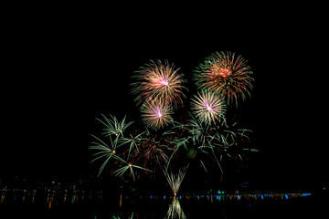 Beautiful fireworks in the night sky on the surface of the water in the park.