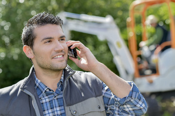 Gardener on telephone, digger in background