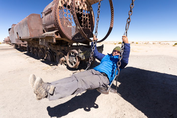 Happy man swinging teeterboard locomotive  Bolivia trains cemetery.