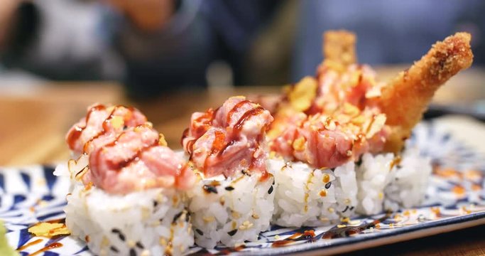 Taking sushi rolls from plate in restaurant