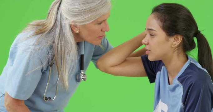 A concussed soccer player is consoled by the team medic on the field on green screen. On green screen to be keyed or composited. 