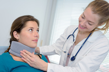 smiling female doctor adjusting neck brace on pretty patient