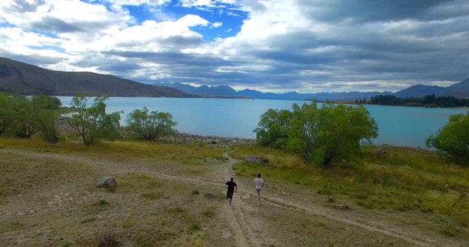 NEW ZEALAND – MARCH 2016 : Aerial shot over people running towards Lake Tekapo on a beautiful day with amazing landscape in view