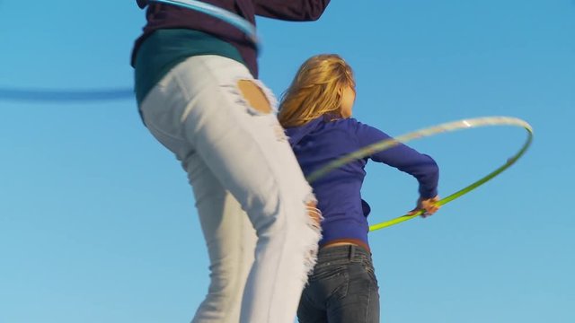 Two women friends with hula hoops at the beach
