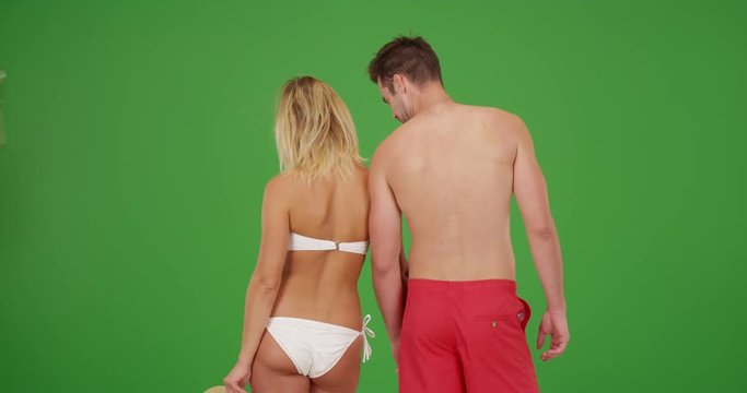 Young attractive millennial couple standing together in their swimsuits on green screen. On green screen to be keyed or composited. 