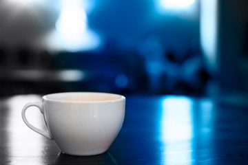 White cup on the table in the cafe gray and blue toning