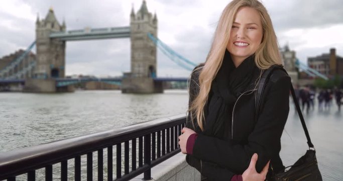 Smiling white British girl laughs with joy near Tower Bridge in London