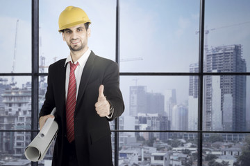 Fototapeta premium Businessman holding blueprints and showing thumb up