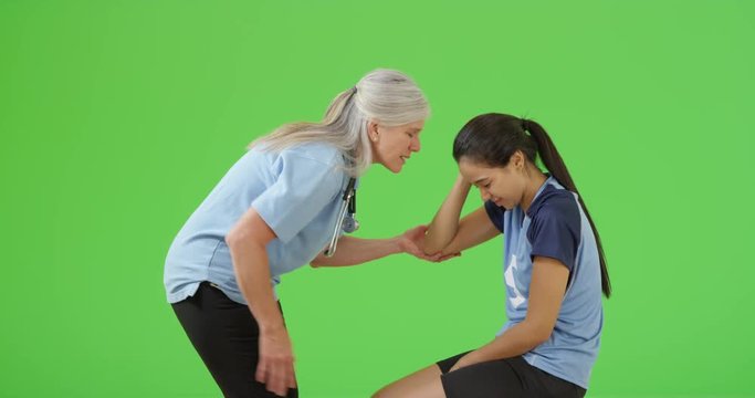 A injured soccer player is checked for a concussion by the field side physician on green screen. On green screen to be keyed or composited. 