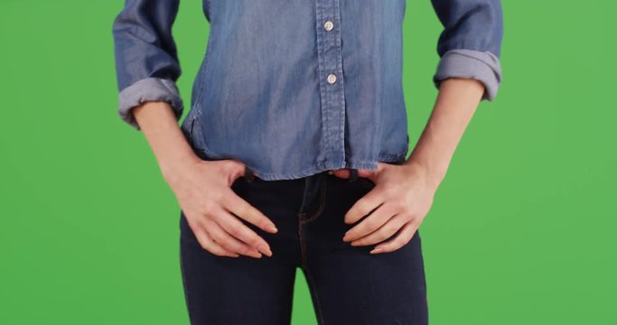 Close up of Caucasian woman hooking thumbs into the belt loop of jeans outside on green screen. On green screen to be keyed or composited. 