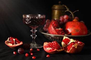 Still life with pomegranates, grapes and a glass of wine