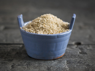 Flaky sea salt with herbs in a blue Cup on a black wooden table.