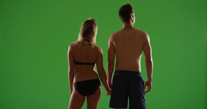Romantic white millennial couple standing together enjoying the sunset at the beach on green screen. On green screen to be keyed or composited. 