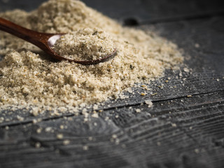 A big pile of salt with herbs with a spoon of wood on a black vintage table.