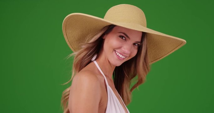 Young Caucasian woman in bikini posing with floppy hat on green screen. On green screen to be keyed or composited.
