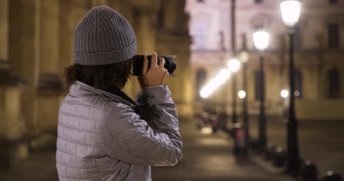 Attractive smiling black female takes photo of French museum at night