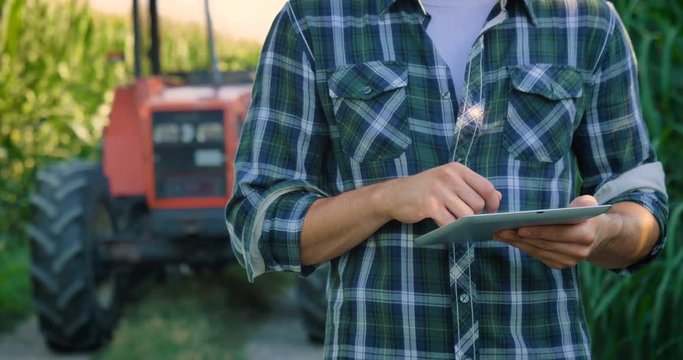 Portrait of a happy young farmer holding fresh vegetables in a basket. background of a tractor and nature Concept biological, bio products, bio ecology, grown by own hands, vegetarians, salads healthy