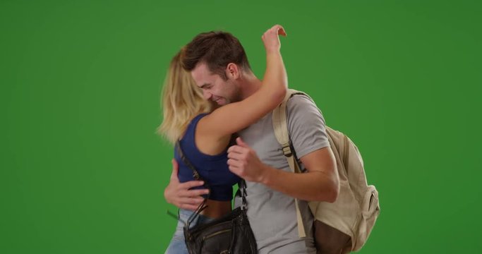 Excited young white woman attack hugs her boyfriend on green screen. On green screen to be keyed or composited. 
