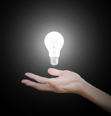 Hand gesture holding floating light bulb with light on dark background. Conceptual thinking new idea. Concept idea.