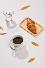 Breakfast with croissant and black coffee composition.