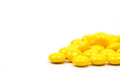 Yellow sugar coated tablets pills on white background with copy space. Medicine for treatment constipation.